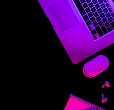 Laptop and notepad on black background with neon light, flat lay, night work concept, copy space.